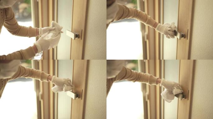 中年妇女用清洁擦拭擦拭门把手。