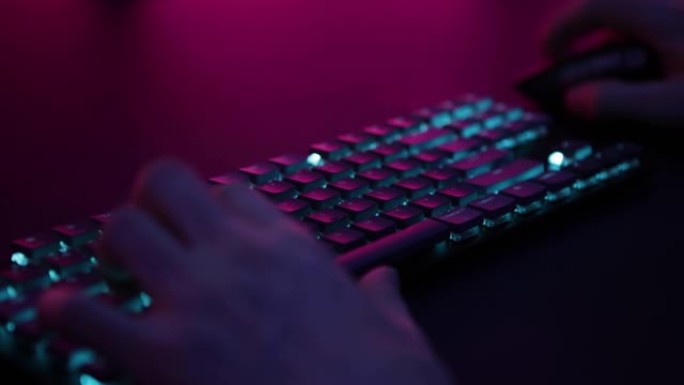 男性手在脉动背光键盘和鼠标上玩电脑游戏。