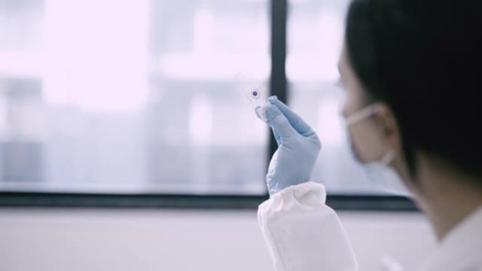一位女科学家分析装在玻璃中的血液样本的4k视频片段