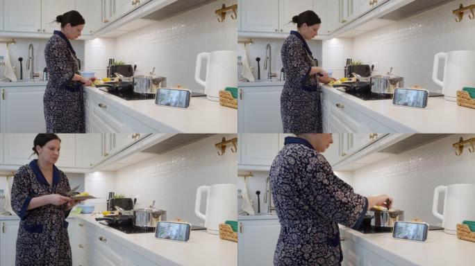 妈妈在厨房里用ip摄像头作为手机上的婴儿视频监视器做饭，女人在智能手机屏幕上实时观看熟睡的婴儿