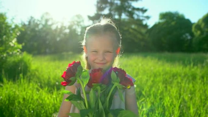 夏天户外，快乐可爱的小女孩带着花束牡丹的肖像。微笑可爱的女孩孩子拿着花在相机里看。童年，幸福，春假，