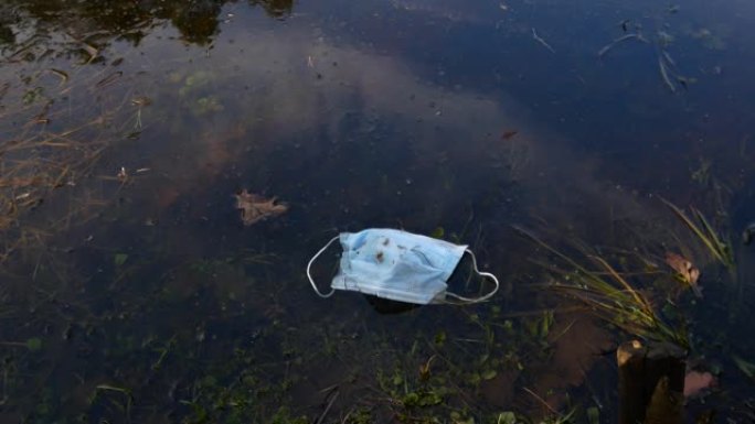 城市湖水中的医用防护口罩。冠状病毒的后果 (新型冠状病毒肺炎)。生态污染，医疗垃圾概念。公园里的垃圾