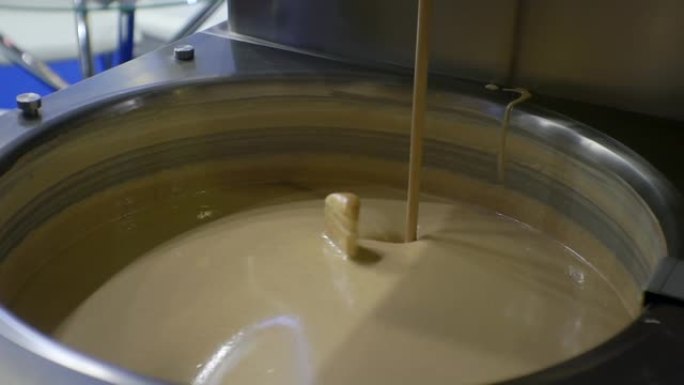 现代食品生产。工艺流程。融化的液体巧克力在大型工业搅拌机中混合。特写