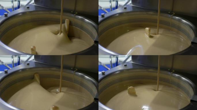 现代食品生产。工艺流程。融化的液体巧克力在大型工业搅拌机中混合。特写