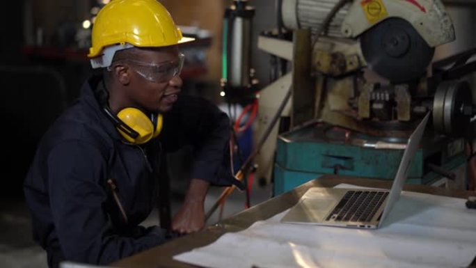工业制造工厂使用笔记本电脑视频会议的安全帽非裔美国工业工程师黑人工厂工人使用带有工程软件的笔记本