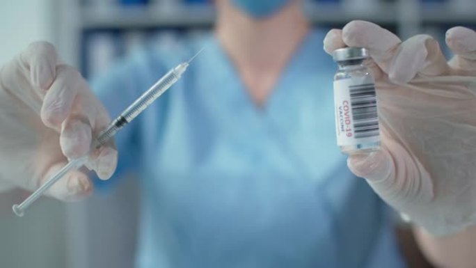 抗大流行药物新型冠状病毒肺炎，身穿蓝色制服和防护手套的医务人员手持玻璃瓶和注射器
