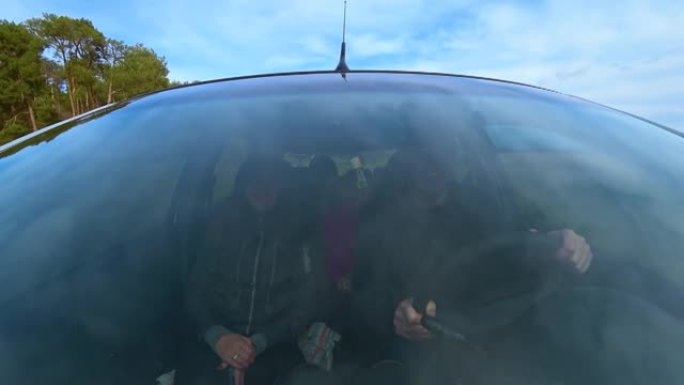 在松树林的乡间小路旁，通过男性和女性的行驶汽车的挡风玻璃观看。民事责任保险的价值