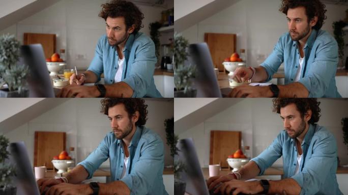 年轻英俊的随便穿衣服的男人在厨房里吃早餐时在网上聊天