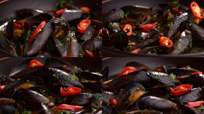 将贻贝的特写镜头与在黑锅中旋转的辣椒片一起旋转。在平底锅里煮香贻贝。