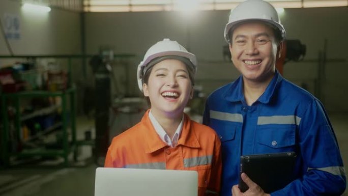 穿着安全制服的亚洲emgineer男女技术员的肖像站着转身看着相机，在机械厂工作场所背景下欢快自信地