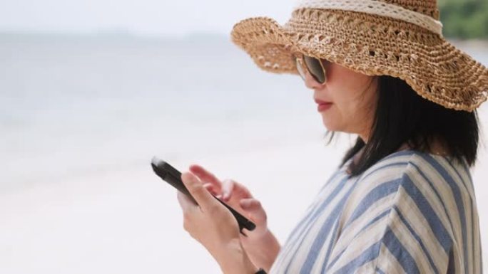 亚洲妇女在暑假时间在海滩上使用手机。独自旅行