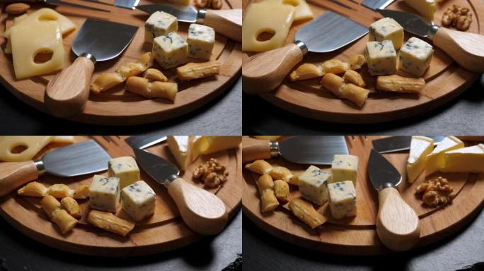 切片奶酪、坚果、葡萄、蜂蜜和小刀放在木盘上。旋转