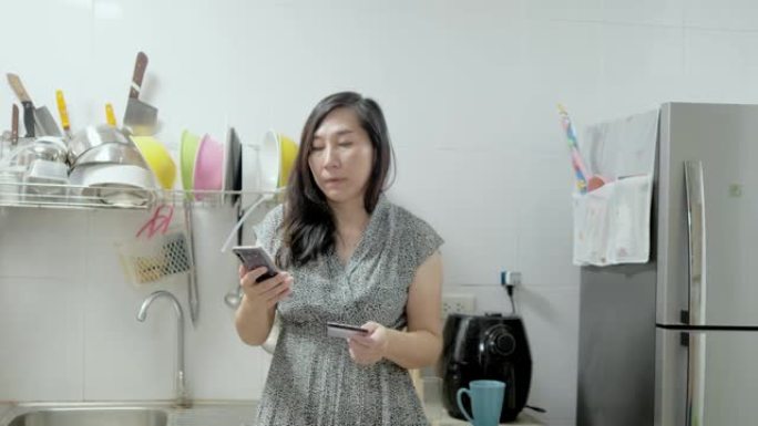 亚洲女性在线购物并在家厨房处理付款，检疫生活方式理念。