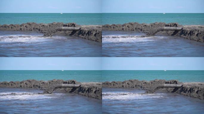 泥浆以慢动作从海滩上的管子中流出