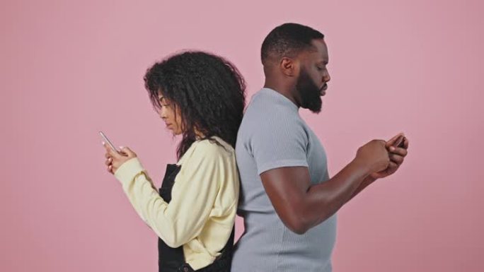 小工具成瘾。年轻的非洲裔美国男女在智能手机上浏览，背靠背，彼此无视