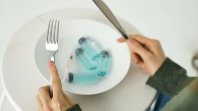 女人要从白色盘子里吃，里面有蓝色液体的玻璃安瓿，接种概念，顶视图