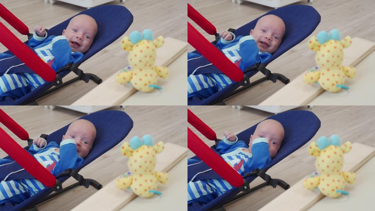 快乐微笑的男婴坐在摇椅上，为新生儿悬挂摇铃玩具