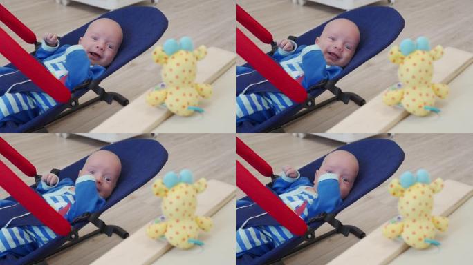 快乐微笑的男婴坐在摇椅上，为新生儿悬挂摇铃玩具