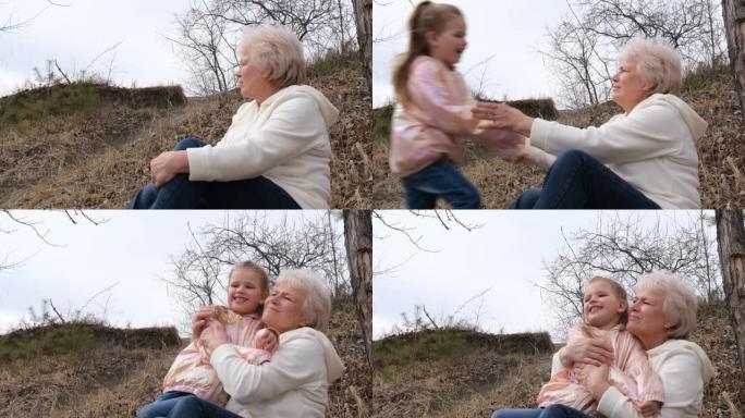 可爱的孙女拥抱着她的祖母。幸福的家庭。和祖父母在户外玩得开心