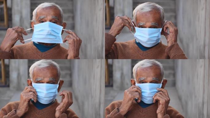 戴着面具挣扎的印度老人的肖像。坐在室内。在电晕病毒大流行2021年中老年人戴口罩的认识