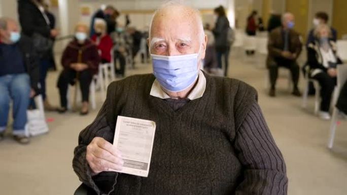 戴着面具的温柔爷爷看着身份证。疫苗接种护照。辉瑞生物技术新型冠状病毒肺炎冠状病毒疫苗。远程培训。