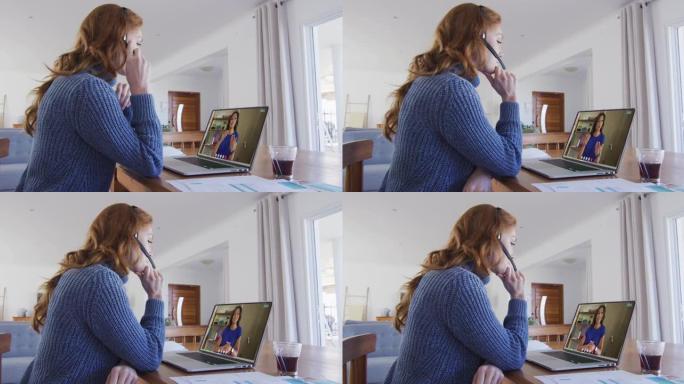 戴着电话耳机的白人妇女在家里的笔记本电脑上与女同事进行视频通话