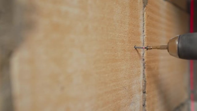 安装金属信标。墙面维修。翻新概念。拧紧墙上的螺丝。工人用钻头拧紧螺丝。