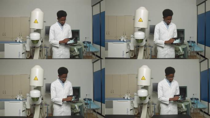 年轻的非洲裔美国男子医生穿着白色制服和眼镜，演示数字平板电脑与超声波扫描，在泌尿外科医疗中心现代超声