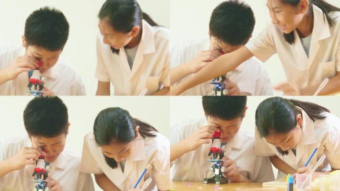 亚洲学童在科学课上穿着实验室外套，一起使用显微镜，教育理念。