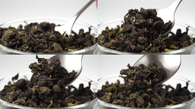 干的滚绿茶叶以慢动作从一茶匙掉成一堆