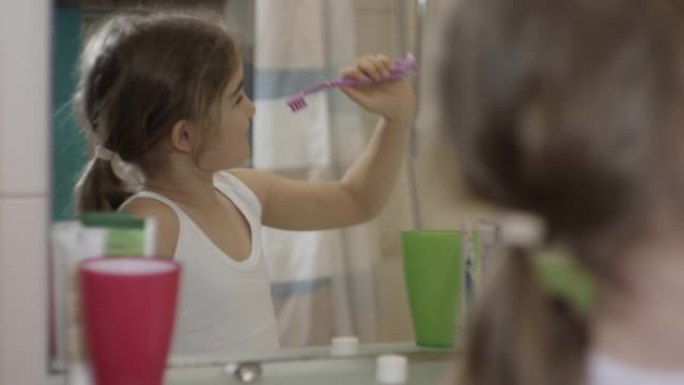特写肖像年轻小女孩在浴室里用牙刷跳舞唱歌看着镜子反射。日常口腔卫生。快乐肖像高加索无牙儿童在浴室跳舞