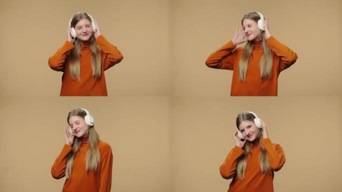 大型无线白色耳机中享受音乐的时尚模特肖像。穿着橙色毛衣的长发年轻时尚女孩在棕色工作室背景下摆姿势。特