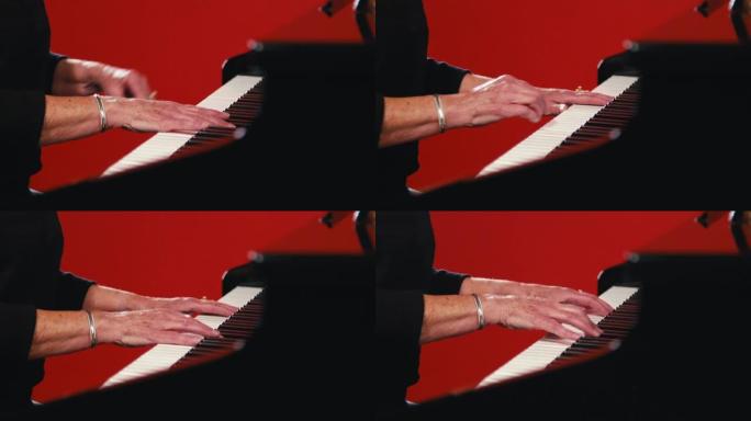 一名成年白人妇女的手准备在红色工作室背景前弹钢琴的特写镜头