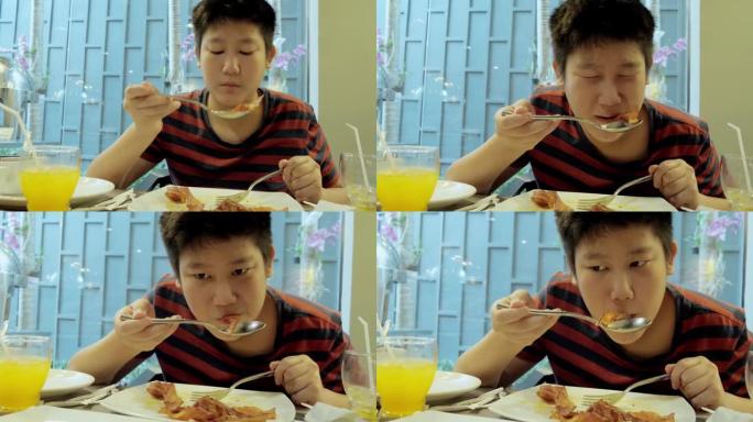 快乐的亚洲男孩在度假旅行期间与家人、生活方式理念在酒店自助餐厅附近享用早餐。