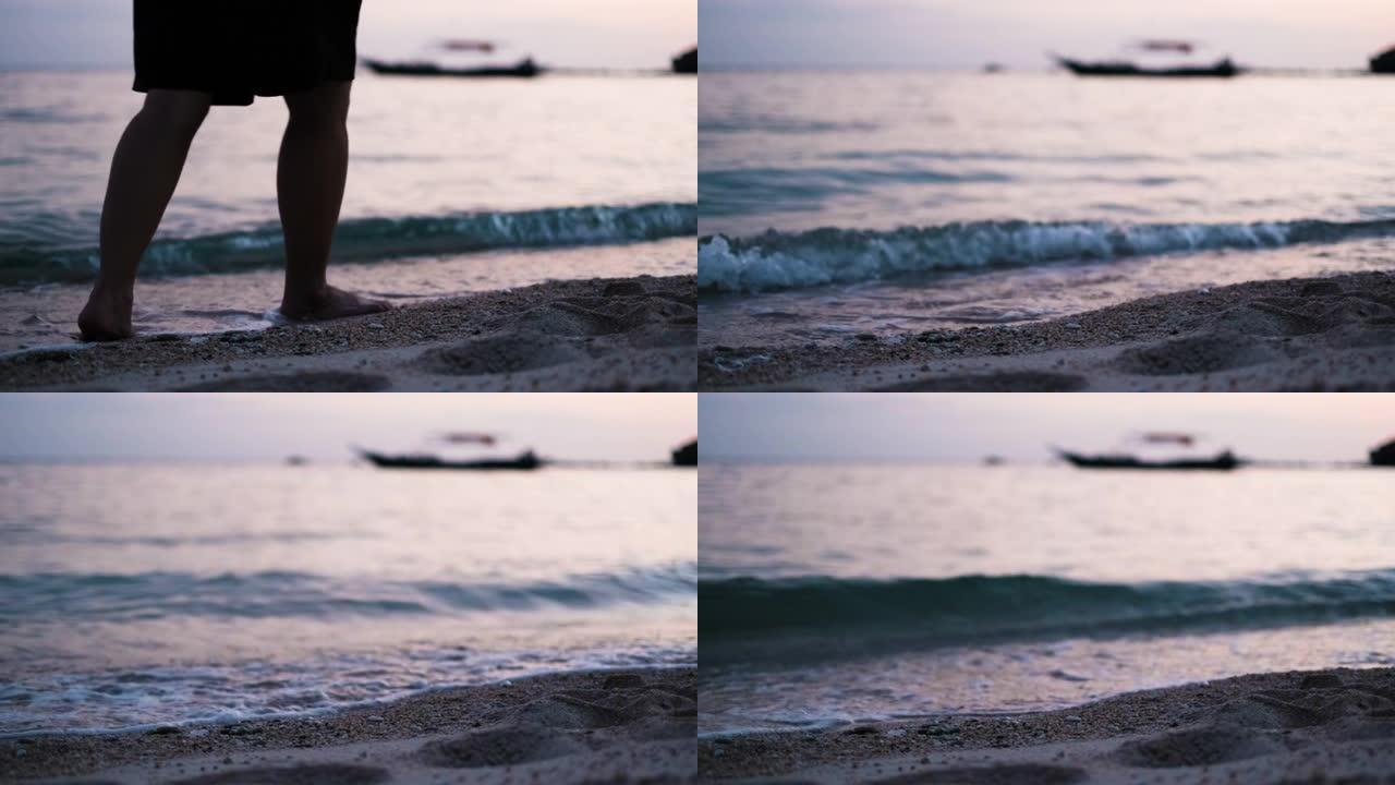 夏季日落时赤脚独自在沙滩上行走的特写，女性的脚踩在海上