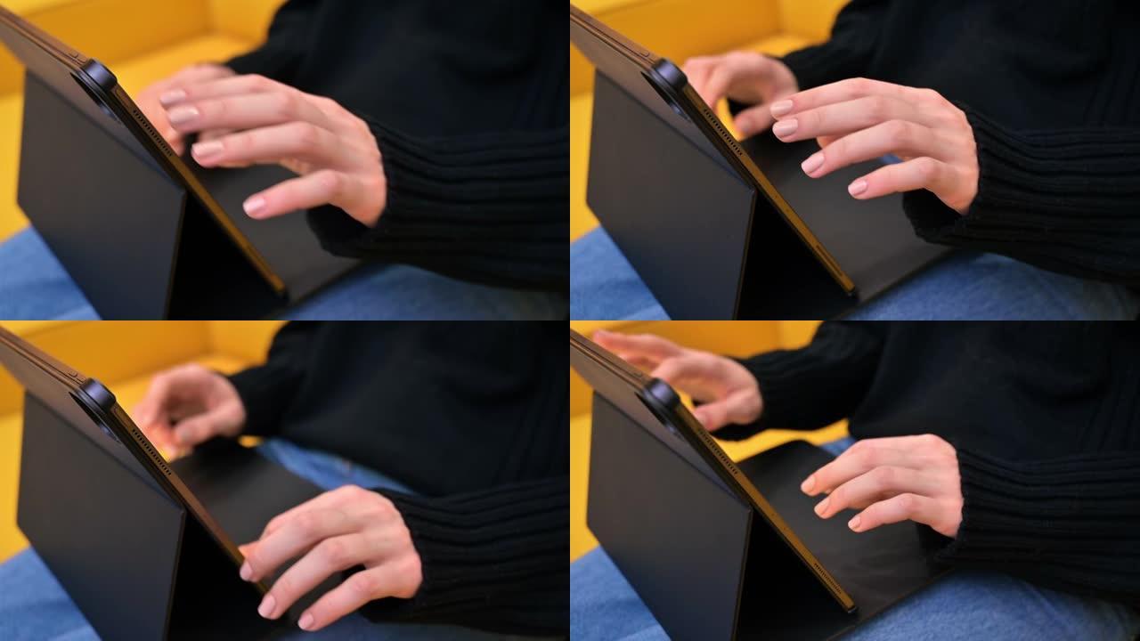 年轻的内容创作者在黄色沙发上使用她的平板电脑。舒适的在家工作环境。关闭打字