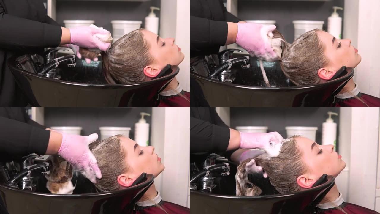 美发师在洗脸盆中客户的湿头发上泡沫洗发水。