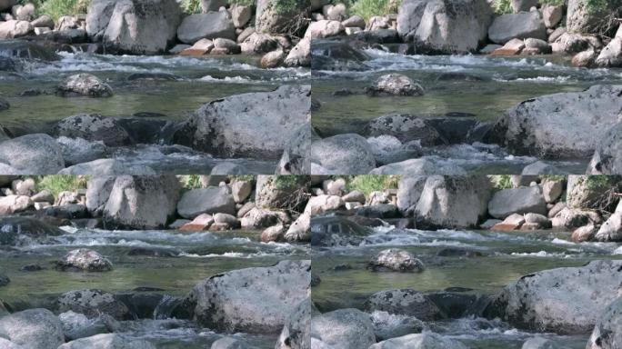 山河在灰色的石头中流动。河床中的水飞溅和冒泡