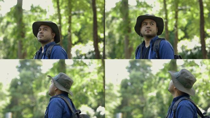 徒步旅行者背着背包在森林里徒步旅行。快乐的亚洲男人站在一起看着美丽的森林。大自然户外的男模。