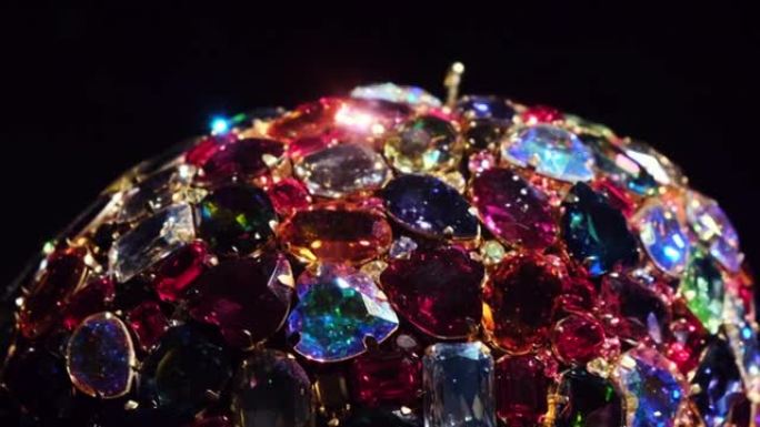由许多发光的水晶或宝石制成的旋转珠宝的特写镜头被隔离在黑色背景上。概念。带有彩色发光宝石的豪华珠宝。