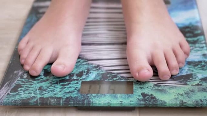 用体重计测量青少年的体重。孩子光着脚检查体重4K