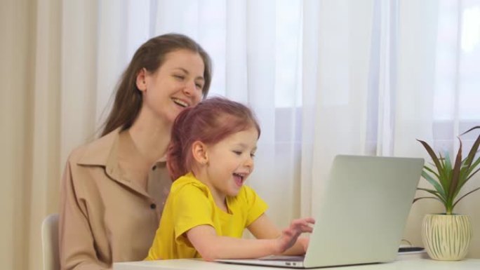 妈妈和女儿用笔记本电脑。女人在家和她的孩子一起工作。一家人一起看平板电脑的屏幕。白人母亲在家工作，有