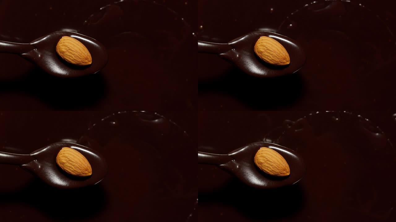融化的液体优质黑巧克力和杏仁旋转，用坚果制作甜甜点的过程