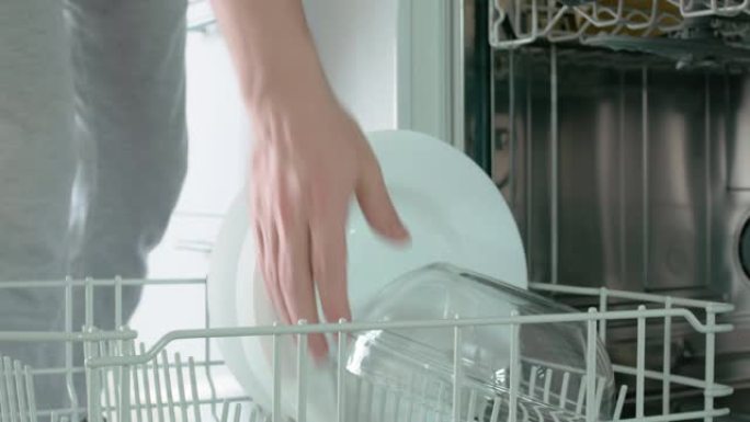 女子打开洗碗机门，拉出底部漆成白色的抽屉，轮流拿出餐具托盘、清碗、白汤碗。特写