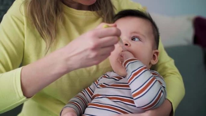母亲用硅胶勺给婴儿喂粥。