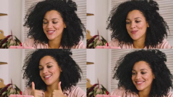 可爱的非洲裔美国妇女使用手机进行视频通话。黑色黑发女人，卷发，坐在明亮的房间里摆姿势。特写。慢动作就