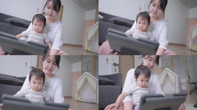 愉快的妈妈和聪明的婴儿在平板电脑上观看在线教育孩子频道，年轻的成年妈妈教女儿回答一个问题，可爱的女婴