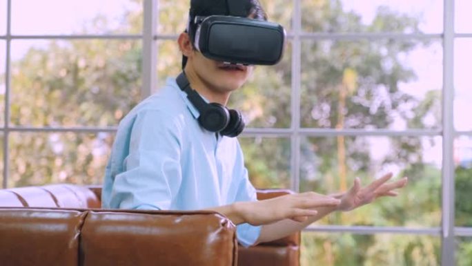 亚洲男子戴VR眼镜在家客厅玩看虚拟现实模拟世界旅行形式回家