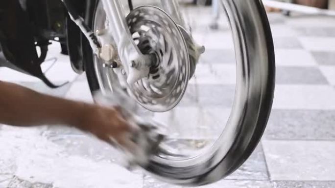 一个男人洗手摩托车前轮的特写镜头。