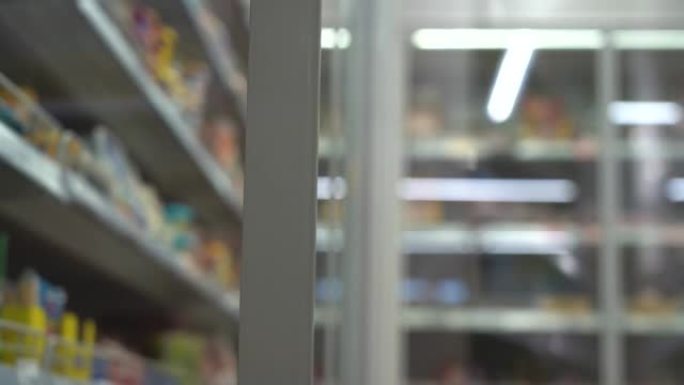 超市里的老人。购物者在商店里打开冰箱。老人在杂货店冰箱里选择食物